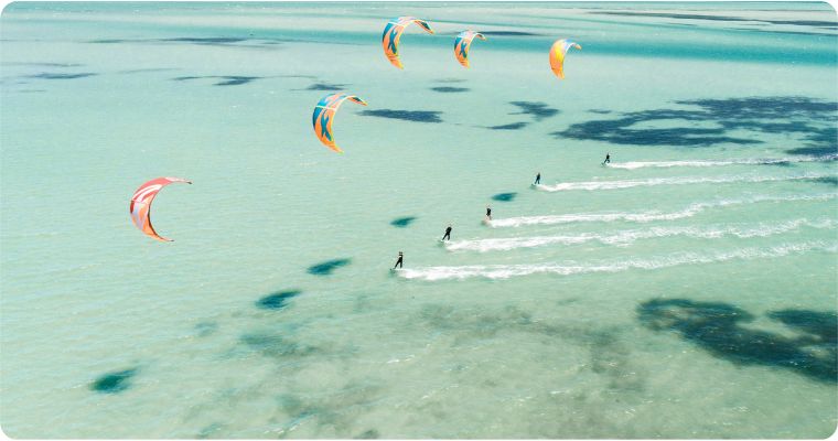 group of people kite surfing on crystal clear water 