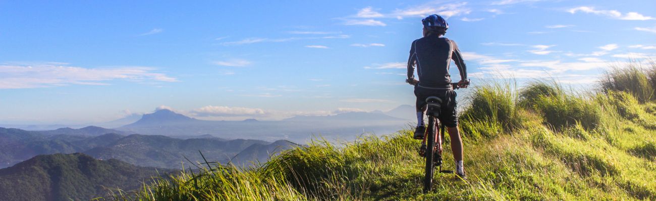 man-on-bike-resting-at-top-of-hill-looking-at-view