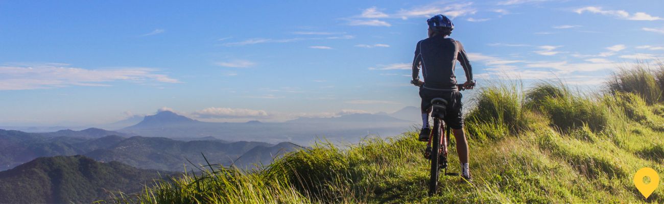 man-on-bike-resting-at-top-of-hill-looking-at-view